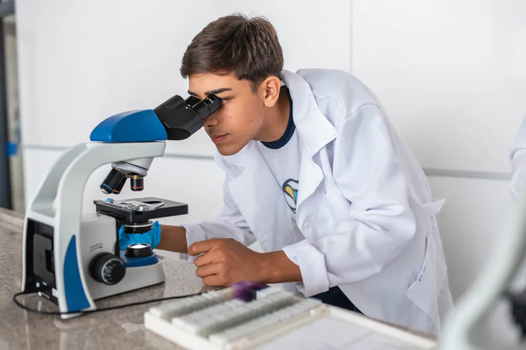 Aluno utilizando microscópio em laboratório